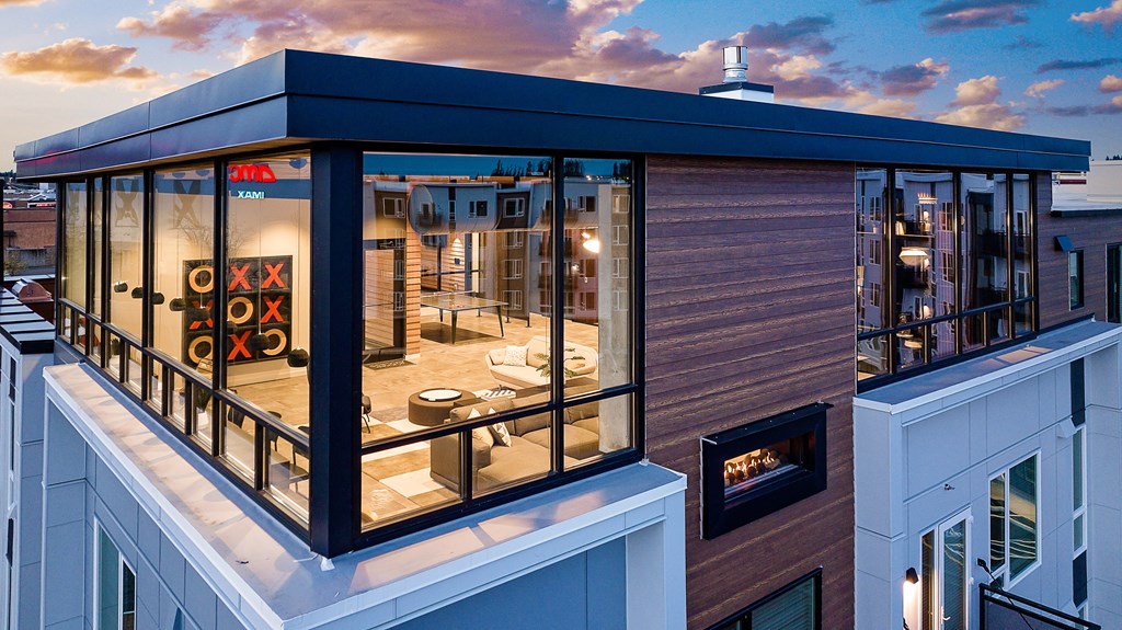 a living room with a fireplace and large windows on the side of a building