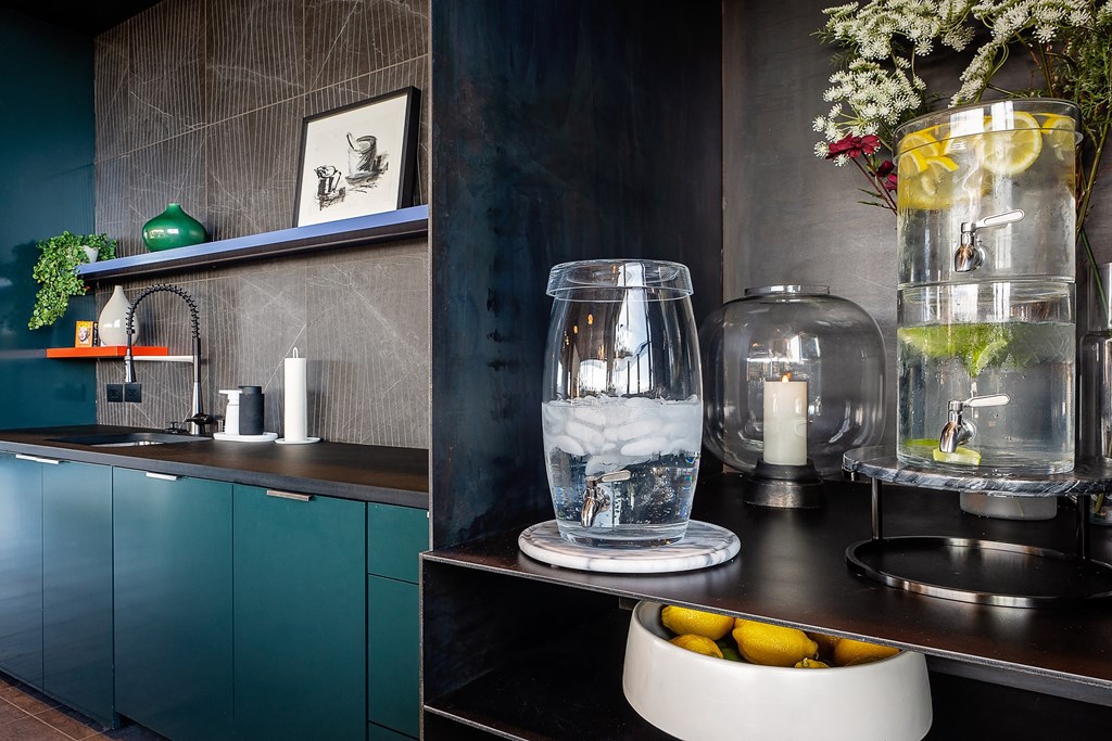 a kitchen with dark blue cabinets and a black countertop with a bowl of fruit and a