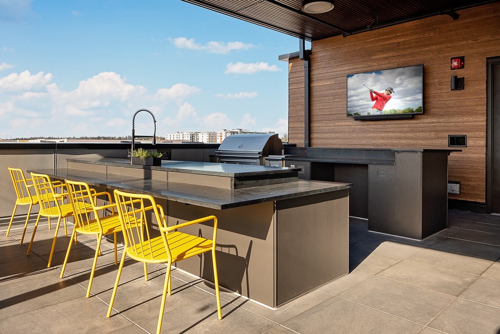 an outdoor kitchen with a bar and yellow chairs