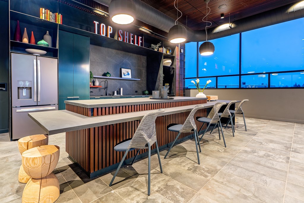 a long table with chairs and stools in front of a large window with a city view
