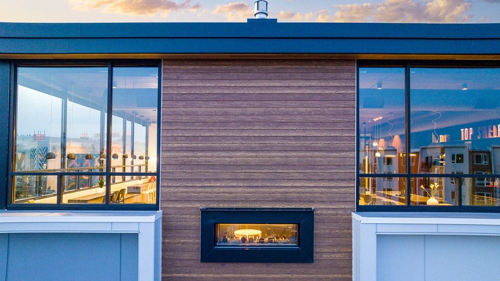 a view of the exterior of a building with a fireplace and large windows