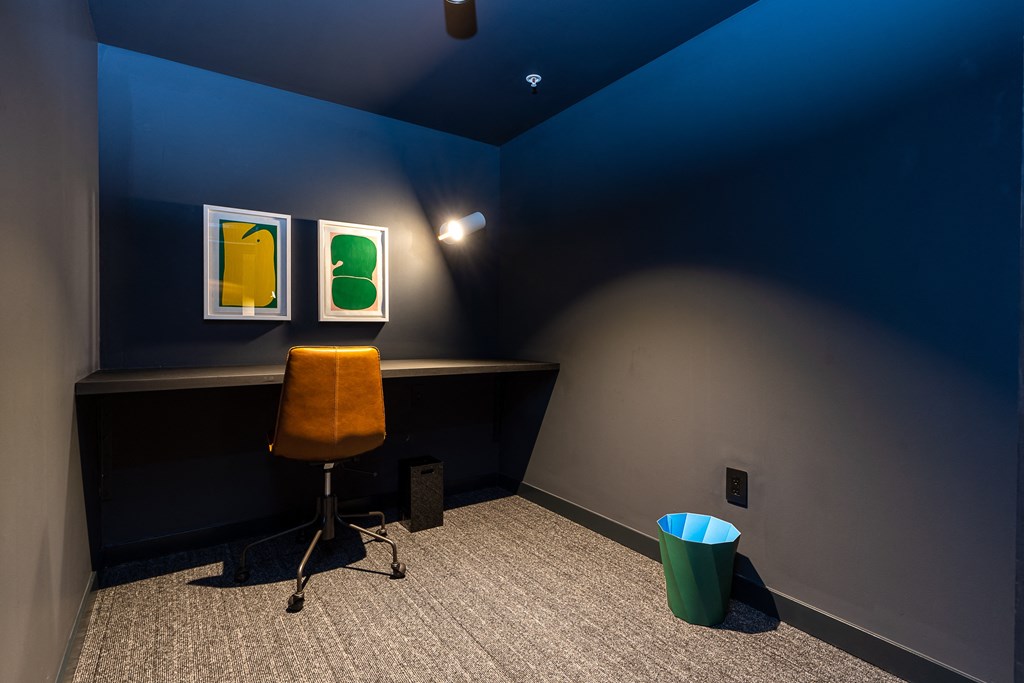 a small room with a desk and chair and two paintings on the wall