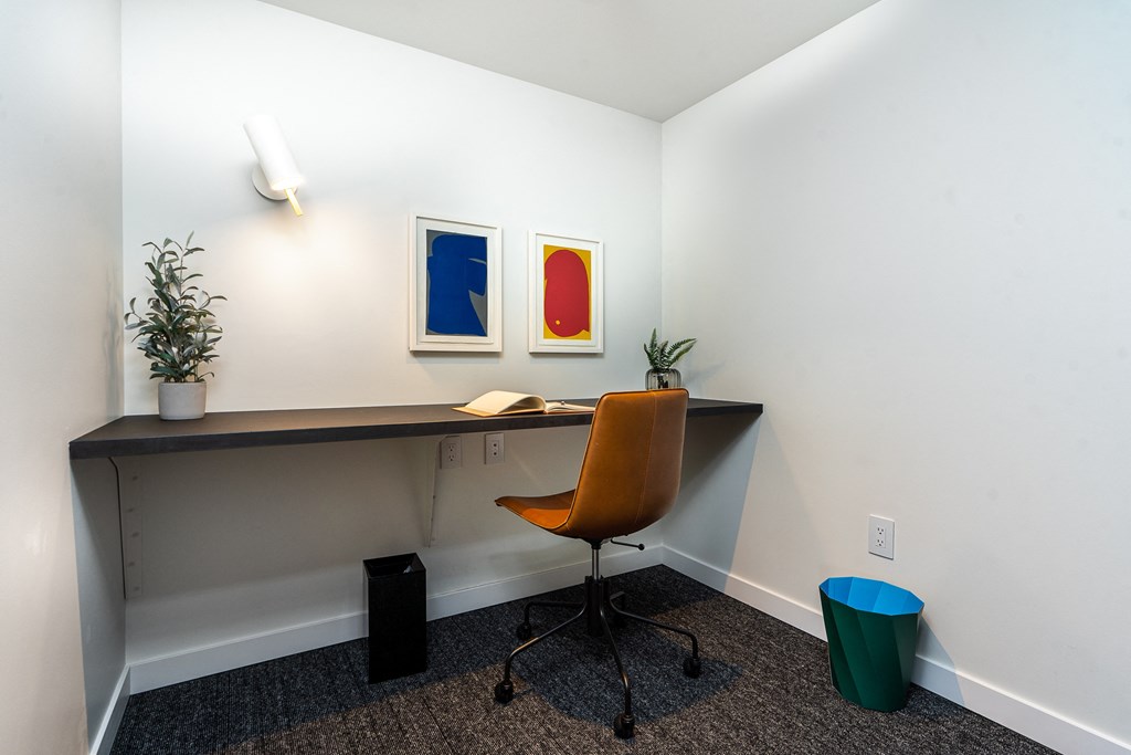 an office space with a desk and chair and two paintings on the wall