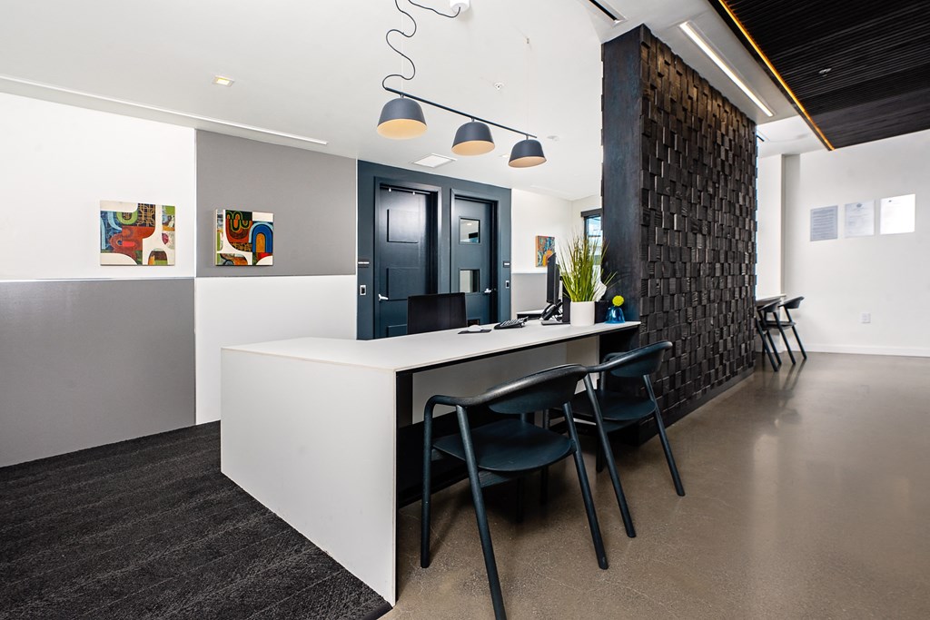 a long white table with black chairs in front of a black brick wall
