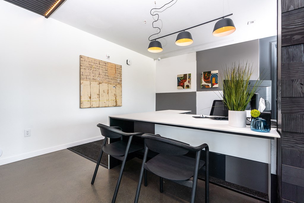 an office space with a white desk and black chairs