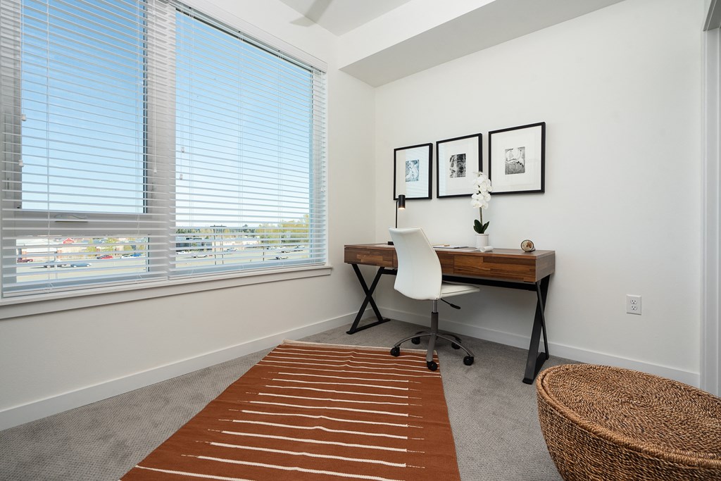 a home office with a desk and chair and a large window