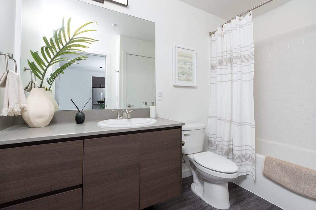 a bathroom with white walls and wood floors