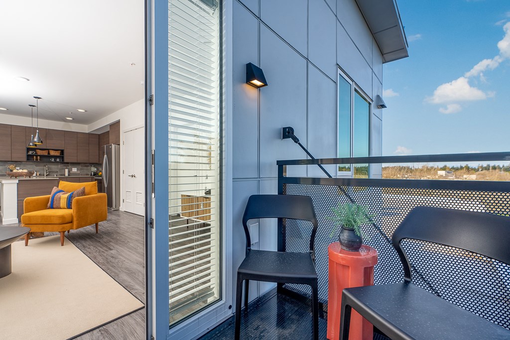a balcony with two chairs and a table and a kitchen in the background