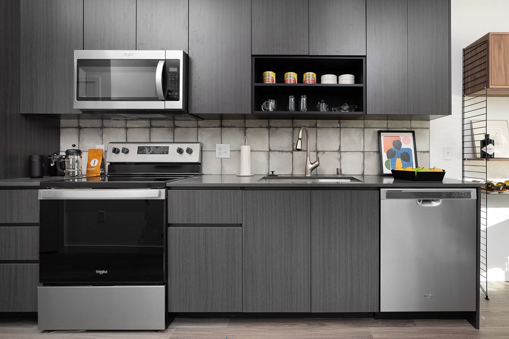 a kitchen with dark gray cabinets and stainless steel appliances