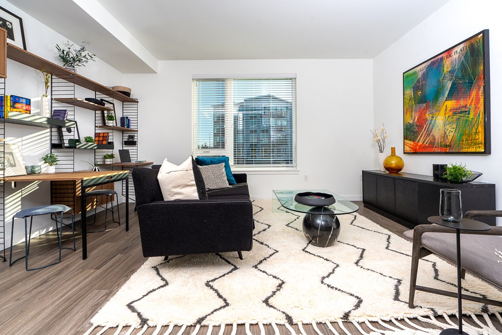 a living room with a black couch and a glass coffee table
