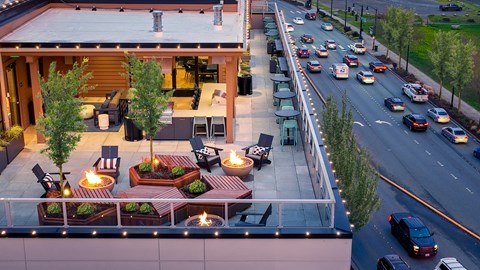 A modern house with a large outdoor seating area overlooking a busy street.