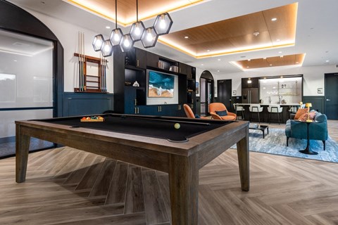 A pool table with a blue rug and a chairs.