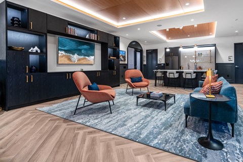 A living room with a blue rug and a painting of a beach scene on the wall.