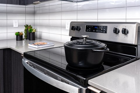 A modern kitchen with a stove top oven and a pot on it.