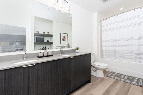 A modern bathroom with a dark wood vanity and white fixtures.