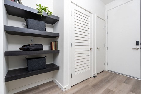 A hallway with a shelf and a door.