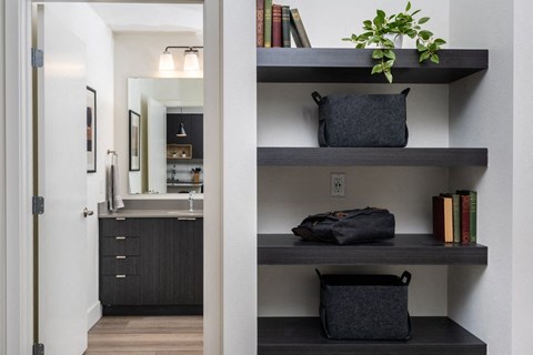 A black bag sits on a shelf next to a plant.