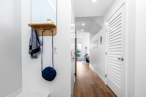 A hallway with a white door and a blue bag hanging on the wall.