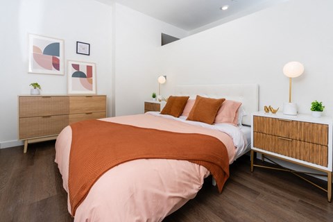 A bedroom with a bed covered in an orange blanket.