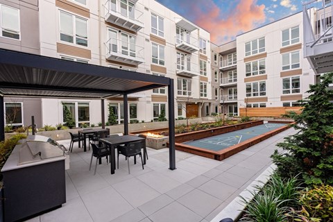 A patio with a table and chairs is surrounded by apartment buildings.