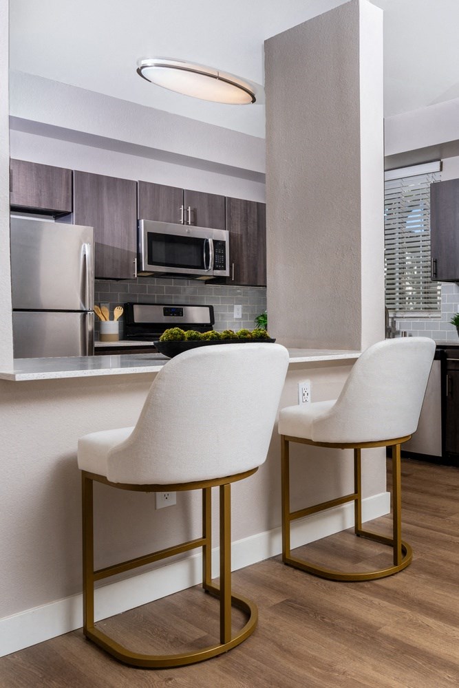 a kitchen with two white chairs in front of a counter