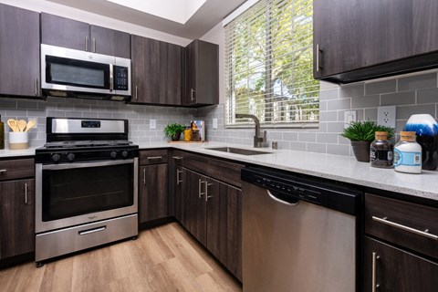 A modern kitchen with dark wood cabinets and stainless steel appliances.