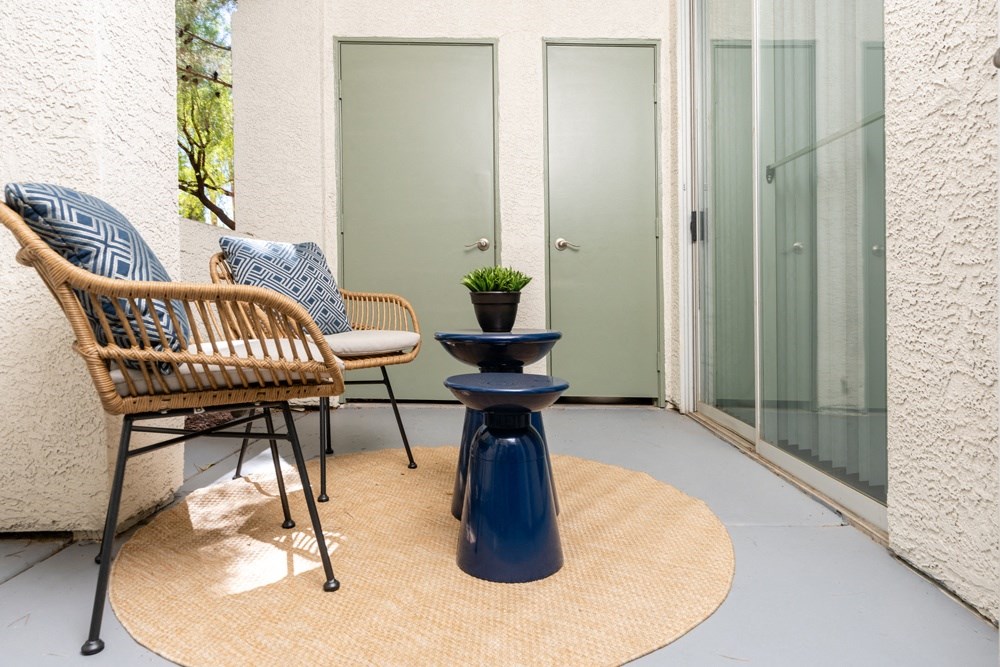 a patio with two chairs and a table and a door