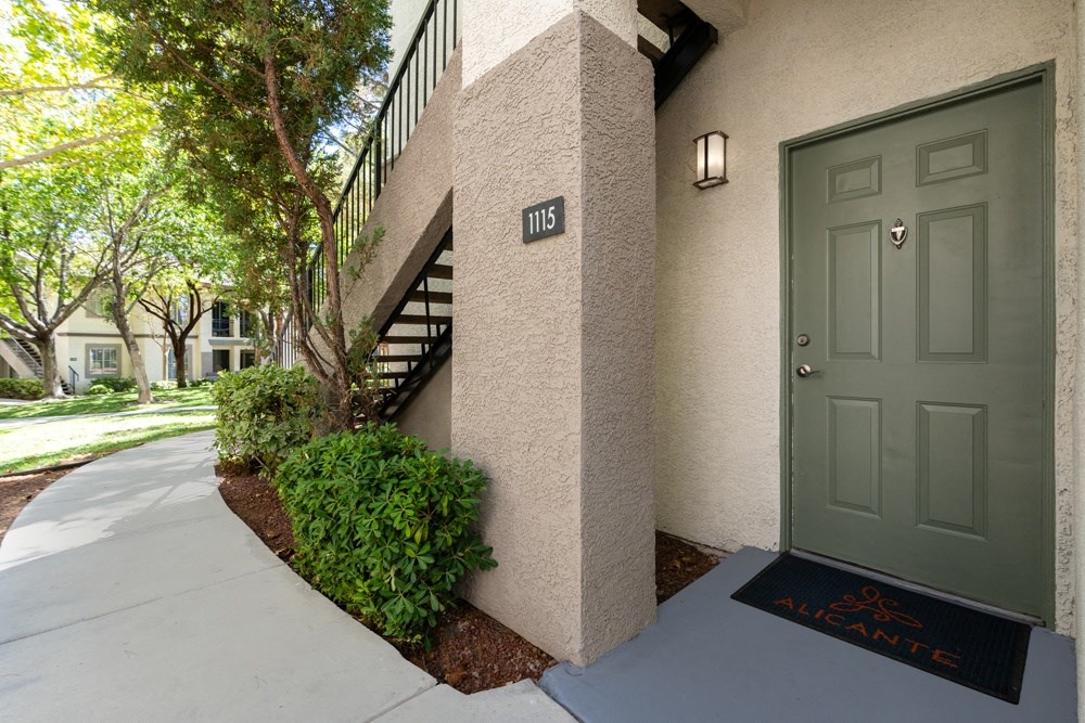the front door of an apartment building with a sidewalk and a green door