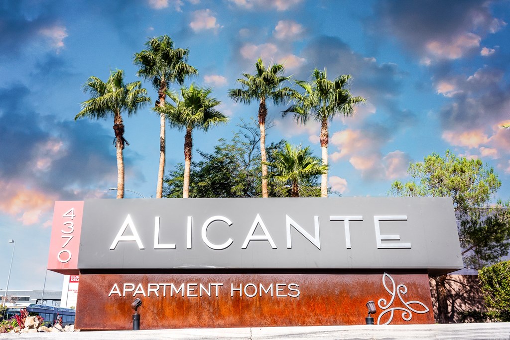 a sign for alicante apartment homes with palm trees