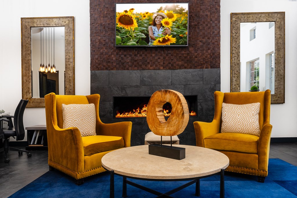 a living room with yellow chairs and a fireplace     and a table