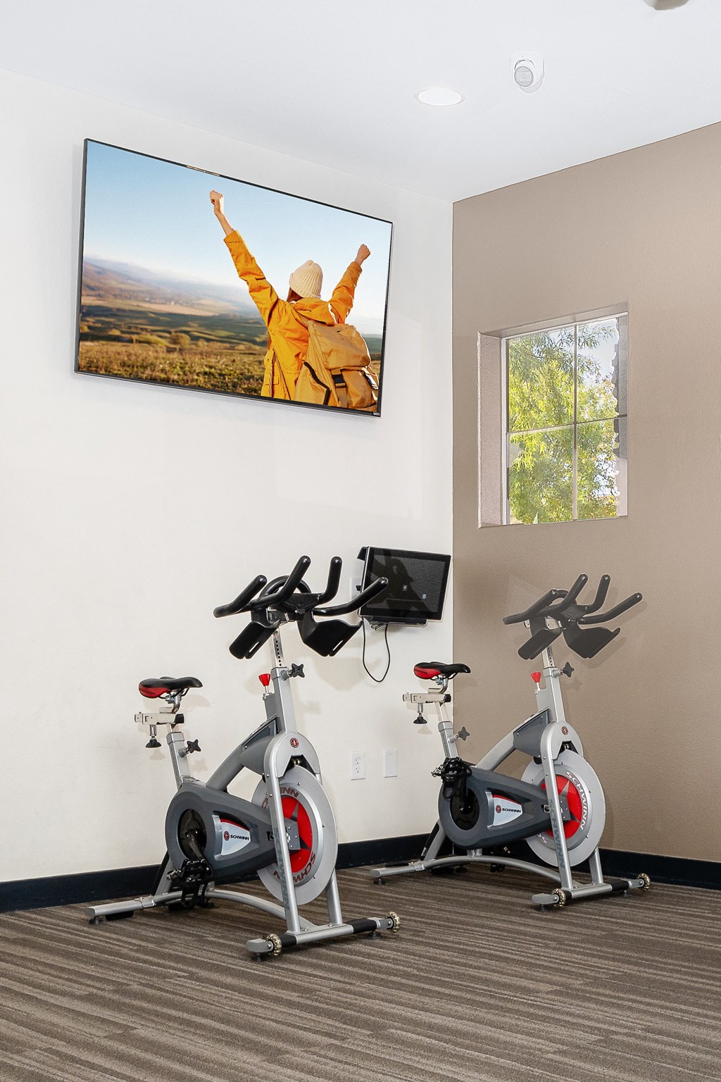 an indoor gym with three exercise bikes and a picture of a man with his arms