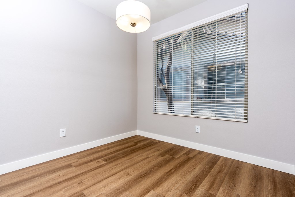 an empty room with wood floors and a window