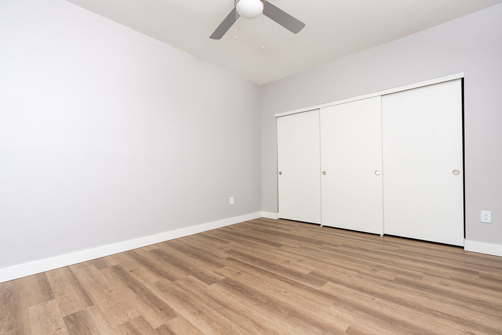 a living room with white walls and wood flooring and a ceiling fan