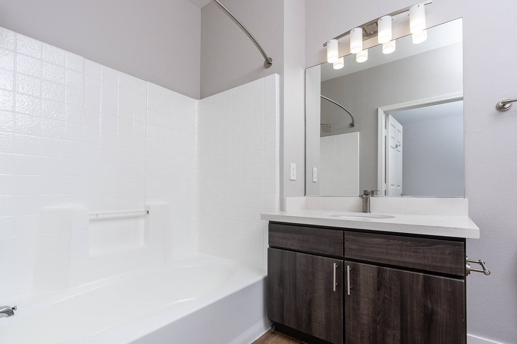 a bathroom with a white tub and a sink and a mirror