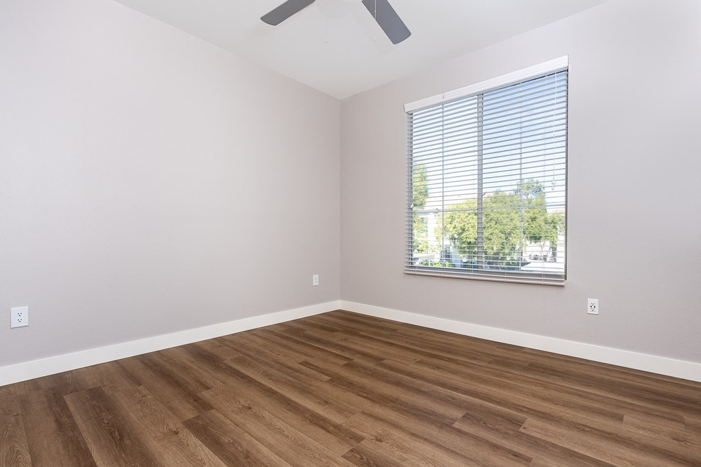 an empty room with wood floors and a window