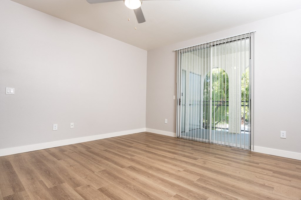 an empty living room with a sliding glass door to a patio