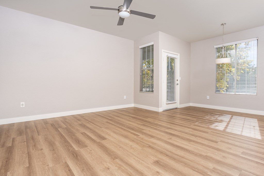 an empty living room with wood floors and a ceiling fan