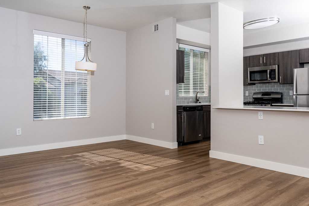 an empty kitchen and living room with wood flooring and a window