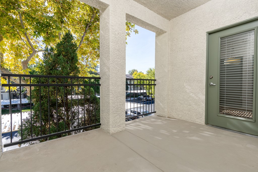 the view from the balcony of a condo with a green door and a balcony railing