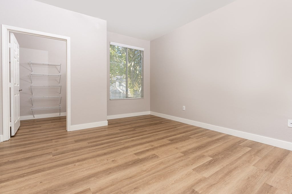 an empty room with wood flooring and a closet