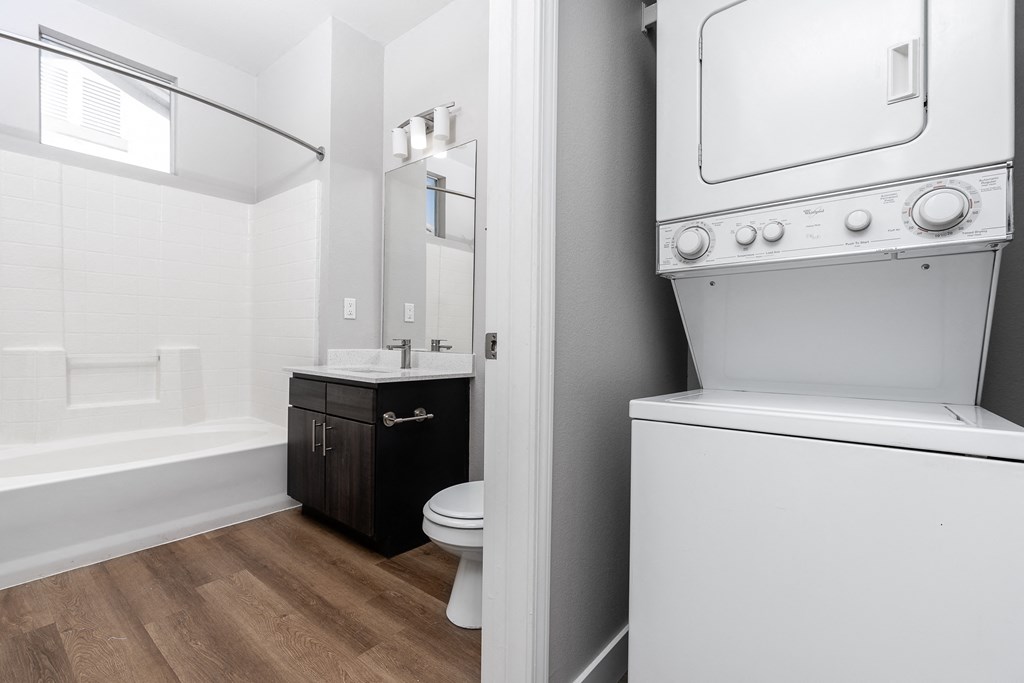 a white washer and dryer in a bathroom with a toilet and a sink