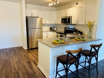 Apartments for Rent in Denver - Allure - Kitchen with Stainless Steel Appliances, Hardwood Flooring, White Cabinets, and Breakfast Bar - Photo Gallery 11