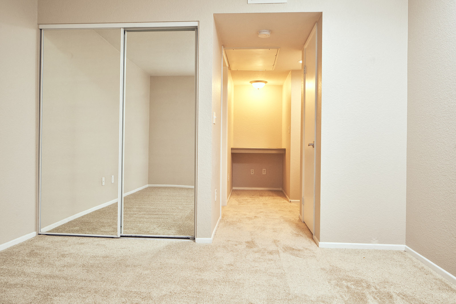 Two-BR Apartments In Escondido, CA - Alta Vista - Spacious Bedroom With Carpet Flooring, Closet with Sliding Mirror Door, And Shelf For Storage