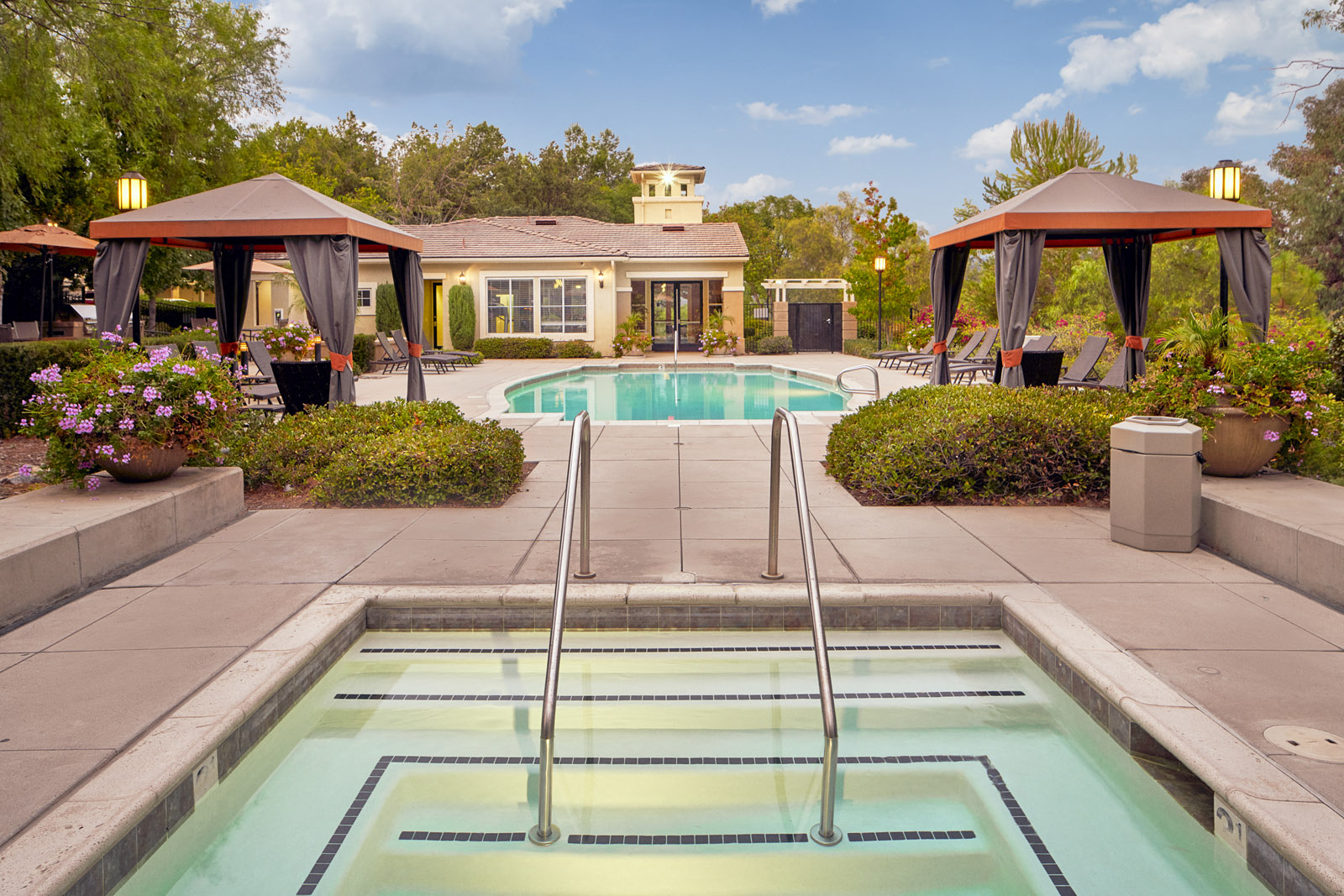 Apartments In Escondido, CA - Alta Vista - Resort-Style Pool And Spa With Cabanas, Lounge Chairs, Grilling Area, and Manicured Shrubs
