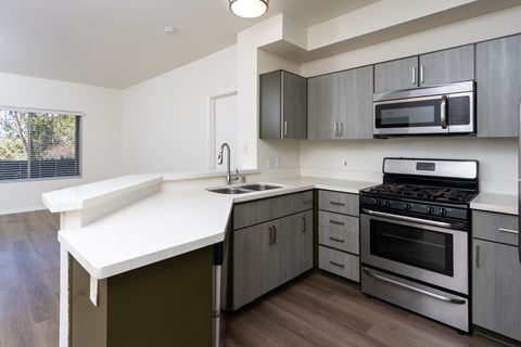 A modern kitchen with a white countertop and stainless steel appliances.