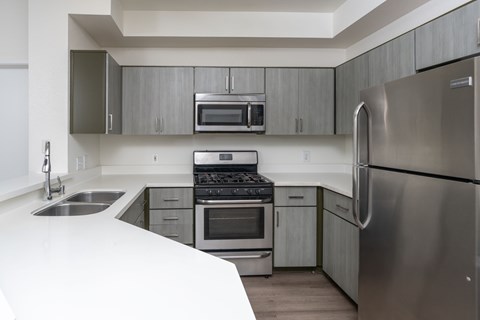 A modern kitchen with stainless steel appliances and white countertops.