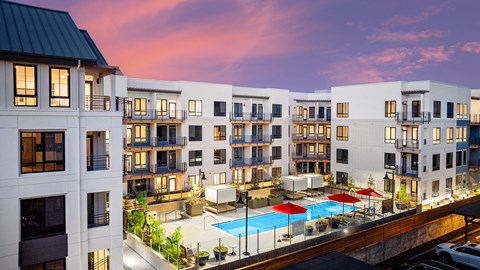 A modern apartment complex with a pool and patio area.