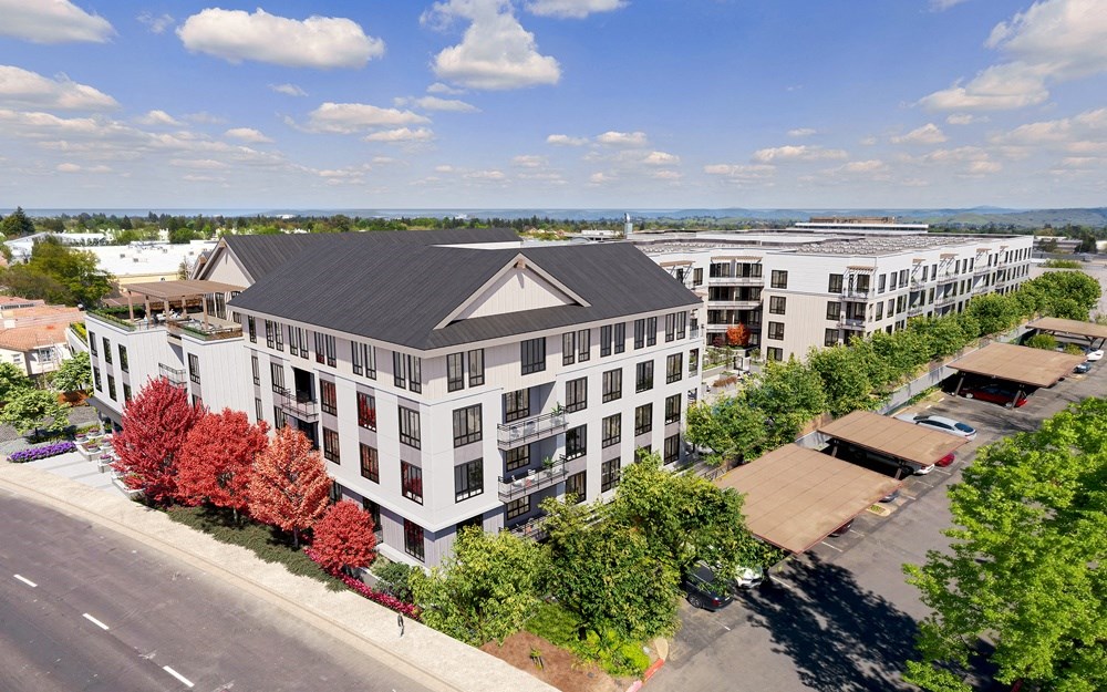 an aerial view of a large white building with a gray roof