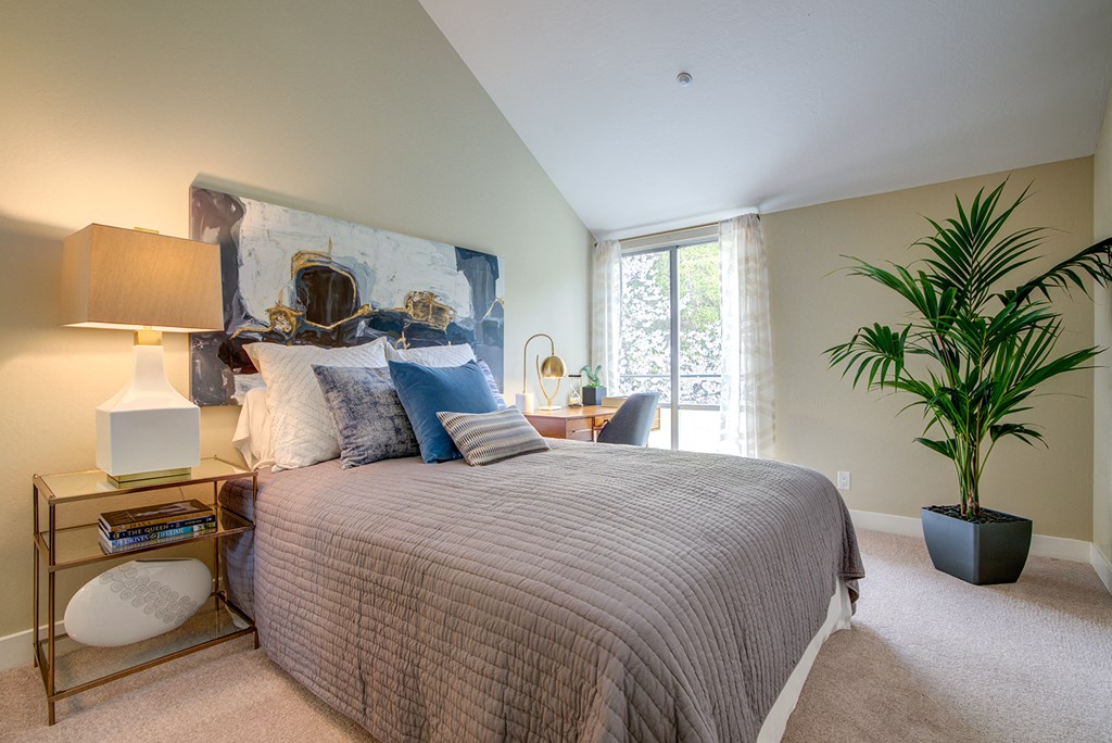 Pet-Friendly Apartments In Mountain View, CA - Americana Apartments - Spacious Bedroom With High Ceilings, Carpet Flooring, And A Window at Americana Apartments, Mountain View, CA