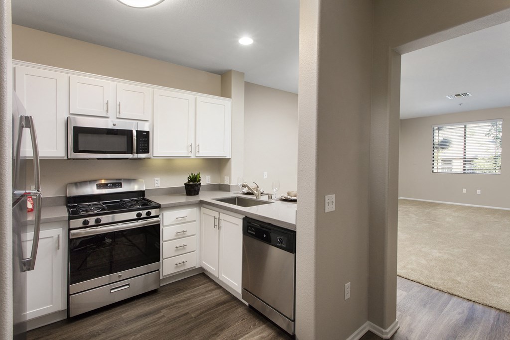 a kitchen with white cabinets and stainless steel appliances at 55+ Remington at Ladera Ranch, California